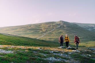 Nipfjället i grönt på sommaren med tre personer på vandring.