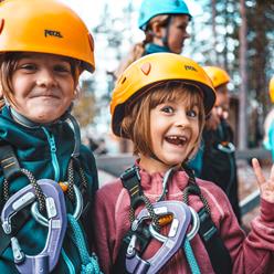 Två barn i förgrunden som är på väg till höghöjdbanan. Fler barn i bakgrunden.